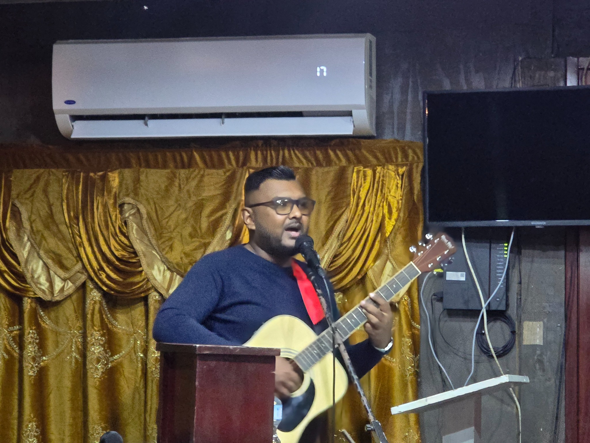 Worship leader singing and playing guitar at Solid Rock Ministries